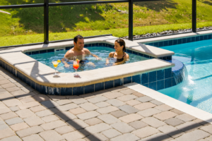 Two adults relaxing in the spa beside the screened swimming pool at Rolling Skies