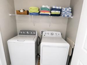 Washer and dryer with shelves of folded towels in the Rolling Skies laundry closet